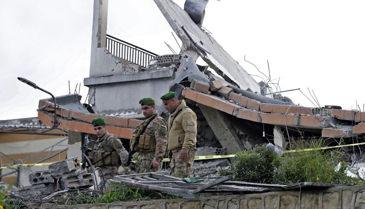 جنود من الجيش اللبناني يقفون في موقع انفجار بمبنى تابع لجمعية كشافة الرسالة في قرية بنعفول (أ ف ب). 