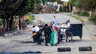 متظاهرون فلسطينيون يرشقون القوات الإسرائيلية بالحجارة خلال مواجهات بعد احتجاج على مسيرة للمستوطنين الإسرائيليين إلى بؤرة حومش الاستيطانية العشوائية في قرية برقة شمال الضفة الغربية المحتلة (19 نيسان 2022، أ ف ب). 