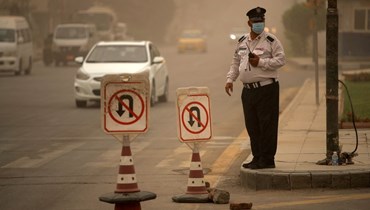 شرطي مرور وقف عند ساحة كهرمانة وسط بغداد خلال عاصفة ترابية (12 نيسان 2022، أ ف ب). 