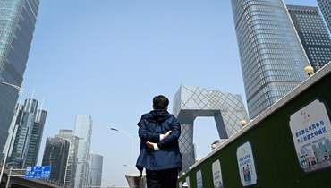 رجل يمشي في شارع في منطقة الأعمال المركزية في بيجينغ (18 نيسان 2022، أ ف ب). 
