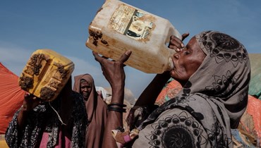هوا محمد إسحاق (الى اليمين) تشرب الماء عند نقطة توزيع للمياه في مخيم مووري في بلدة بيدوا في الصومال (13 شباط 2022، أ ف ب).