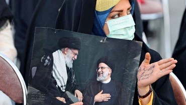 إيرانية ترفع صورة خامنئي ورئيسي.
