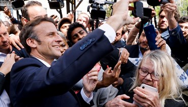 مأكرون (الى اليسار) يلتقط صورة سيلفي مع سكان خلال زيارته سان دوني في ضواحي باريس (21 نيسان 2022، أ ف ب). 