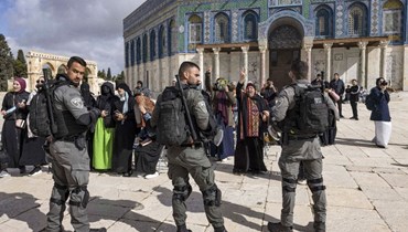 شرطيون إسرائيليون تجمعوا حول نساء مسلمات يصلين أمام مسجد قبة الصخرة في مجمع الأقصى بالبلدة القديمة في القدس (20 نيسان 2022، أ ف ب). 