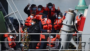 مهاجرون يستعدون للنزول من قارب تابع لحرس الحدود البريطاني في ميناء دوفر في دوفر على الساحل الجنوبي الشرقي لإنكلترا (15 نيسان 2022، أ ف ب). 