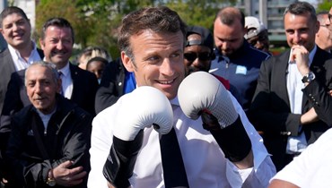 ماكرون وضع قفازات الملاكمة خلال لقائه ملاكما محليا في استاد أوغوست دولون في اطار حملته الانتخابية في سان دوني خارج باريس (21 نيسان 2022، أف ب). 