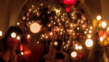 مقدونيون أرثوذكس يحملون الشموع خلال مشاركتهم في قداس عيد الفصح في منتصف الليل في دير سان جوفان بيجورسكي في مافروفو غرب العاصمة سكوبي (24 نيسان 2022، أ ف ب). 