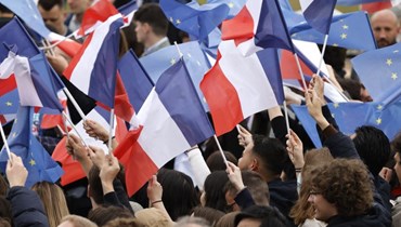 جمهور فرنسي يرفع الأعلام الفرنسية في باريس (أ ف ب).