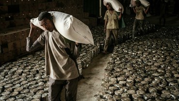 عمال يحملون أكياساً من الطحين لتوزيع مساعدات غذائية على نازحين فرّوا من العنف في إقليم تيغراي (أ ف ب).