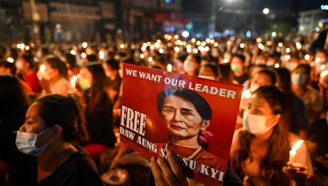 متظاهر يحمل صورة أونغ سان سو تشي خلال وقفة احتجاجية في ضوء الشموع لتكريم ضحايا الانقلاب العسكري في يانغون (13 آذار 2021، أ ف ب).