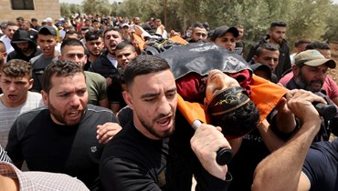 فلسطينيون يحملون جثمان أحمد مساد خلال تشييعه في قرية برقين غرب جنين بالضفة الغربية المحتلة (27 نيسان 2022، أ ف ب). 