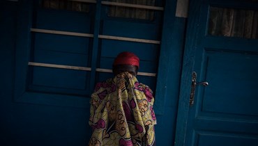 امرأة تخفي وجهها خلال انتظارها خارج مركز صحي في موهيتو بمقاطعة شمال كيفو شرق جمهورية الكونغو الديمقراطية (28 آذار 2022، أ ف ب). 