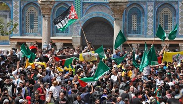 متظاهرون فلسطينيون يلوحون بالأعلام الفلسطينية والإسلامية خلال تجمعهم في المسجد الأقصى بالقدس بعد صلاة الجمعة (29 نيسان 2022، أ ف ب). 