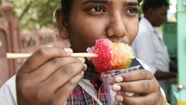طالبة تستمتع بمثلجات خلال يوم صيفي حار في أمريتسار بالهند (28 نيسان 2022، أ ف ب). 