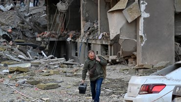 رجل حمل مقتنياته لدى مغادرته مبنى مدمّرا بعد ضربات روسية في كييف (29 نيسان 2022، أ ف ب). 