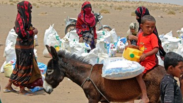 عائلات يمنية تنقل مساعدات من منظمة خيرية في محافظة لحج في جنوب اليمن (أ ف ب).