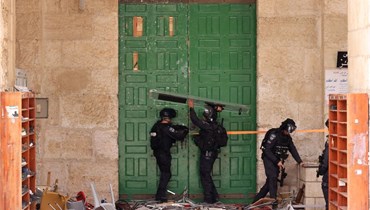 عناصر من الشرطة الاسرائيلية يقفلون باب المسجد الأقصى خلال المواجهات (5 ايار 2022، أ ف ب). 