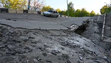 سيارة تمر على جسر مدمر بالقرب من قرية بيتشينيغي في منطقة خاركيف (5 ايار 2022، أ ف ب). 