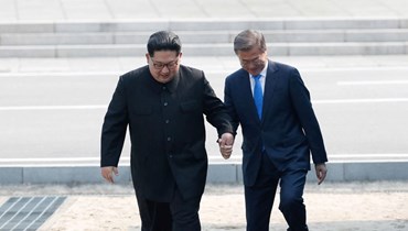 صورة ارشيفية- زعيم كوريا الشمالية كيم جونغ أون (إلى اليسار) ورئيس كوريا الجنوبية مون جاي إن (إلى اليمين) يعبران خط الترسيم العسكري الذي يقسم بلادهما قبل اجتماعهما في قمة في بانمونجوم (27 نيسان 2018، أ ف ب). 