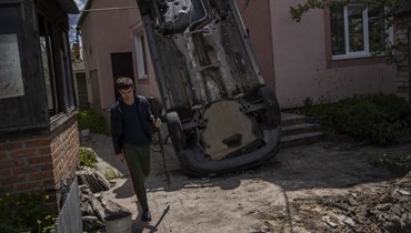 رجل حمل مجرفة لإزالة الركام من منزله المتضرر من جراء القصف في خاركيف (16 ايار 2022، أ ب). 