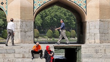إيرانيون جلسوا على جسر خاجو الشهير فوق نهر زيانده رود في أصفهان (16 ايار 2022، أ ف ب). 