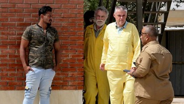 فيتون (الى اليسار) وووالدمان يرتديان الزي الأصفر للمعتقلين لدى وصولهما إلى محكمة في بغداد (22 ايار 2022، أ ف ب). 