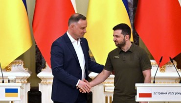 مصافحة بين زيلينسكي (إلى اليمين) ودودا خلال مؤتمر صحافي عقب محادثاتهما في كييف (22 ايار 2022، أ ف ب). 