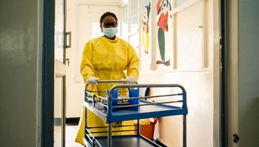 صورة تعبيرية- ممرضة تدفع عربة في ممر في جناح طبي في مستشفى محلي في هراري (26 نيسان 2022، أ ف ب).