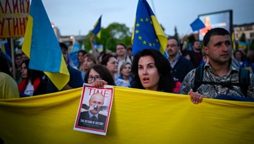 متظاهرون يحملون العلم الأوكراني خلال احتجاج على الغزو الروسي لأوكرانيا أمام السفارة الروسية في صوفيا (9 ايار 2022، أ ف ب). 