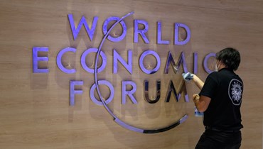 موظفة تنظف شعار المنتدى الاقتصادي العالمي في مركز المؤتمرات في دافوس (أ ف ب).