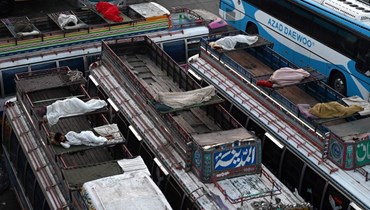 السائقون ينامون على سطح الحافلات المتوقّفة في باكستان (أ ف ب).