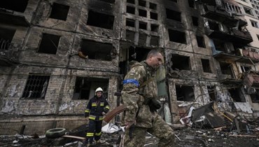 جندي ورجل إطفاء أوكرانيان أمام مبنى مدمر في كييف، آذار 2022 - "أ ب"