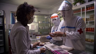 طبيب (الى اليمين) من الجيش الشعبي الكوري يزور صيدلية لإعطاء امرأة وصفة طبية في بيونغ يانغ (27 ايار 2022، أ ف ب). 