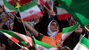 إيرانيون يلوحون بالعلم الوطني خلال تجمعهم في ملعب آزادي بطهران لحضور عرض لأغنية "سلام فارمنده" (26 ايار 2022، أ ف ب). 