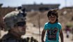 طفل سوري إلى جانب أحد أفراد القوات الأميركية في ريف الرميلان في الحسكة بالقرب من الحدود التركية (أ ف ب).