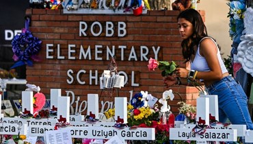 فتاة تضع الزهور في نصب تذكاري مؤقت في مدرسة روب الابتدائية في يوفالدي في تكساس (أ ف ب).