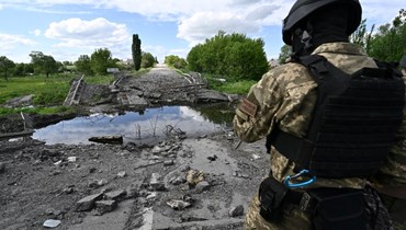 جندي أوكراني يقف بجوار جسر مدمر بالقرب من قرية روسكا لوزوفا شمال خاركيف (28 ايار 2022، أ ف ب). 