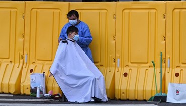 رجل يقص شعره في شارع بجوار حي مغلق في منطقة جينغان في شنغهاي (30 ايار 2022، أ ف ب). 