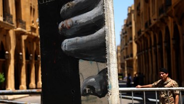 عمال يزيلون أجزاء من حاجز خرساني عند مدخل مجلس النواب في بيروت (27 ايار 2022، أ ف ب). 
