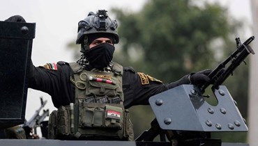 عنصر من قوات الأمن العراقية من تحالف الحشد الشعبي يراقب جنازة رمزية في ساحة التحرير ببغداد (29 ك1 2021، أ ف ب).