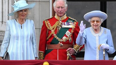 الملكة إليزابيث الثانية ملوحة خلال وقوفها على شرفة قصر باكنغهام، مع ابنها الأمير تشارلز وزوجته كاميلا لمشاهدة عرض جوي في لندن، مع بدء احتفالات اليوبيل البلاتيني (2 حزيران 2022، أ ف ب). 