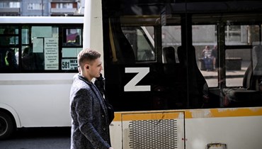 رجل في موسكو يمرّ قرب حافلة لصق على نافذتها الحرف Z، الذي أصبح رمزًا لدعم العمل العسكري الروسي في أوكرانيا (2 حزيران 2022، ا ف ب). 