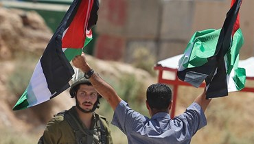 متظاهر فلسطيني يواجه جنديا اسرائيليا في مدينة طوباس خلال تجمع للتنديد بالتوسع الاستيطاني الإسرائيلي في غور الأردن (6 حزيران 2022، أ ف ب). 
