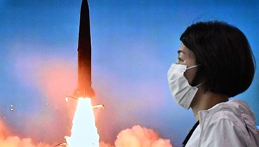 امرأة تمر قرب شاشة في محطة قطارات في سيول، تُظهر بثًا إخباريًا عن اختبار صاروخ كوري شمالي (5 حزيران 2022، أ ف ب). 
