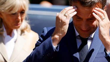 ماكرون لدى وصوله برفقة زوجته بريجيت الى مركز اقتراع في لوتوكيه شمال فرنسا للتصويت في الانتخابات البرلمانية الفرنسية (12 حزيران 2022، أ ف ب). 