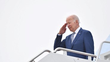 بايدن يلقي تحية عند باب الطائرة الرئاسية قبل الاقلاع من قاعدة أندروز الجوية في ماريلاند (14 حزيران 2022، أ ف ب). 