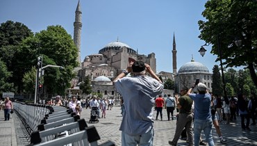 سياح يلتقطون صورًا لمسجد آيا صوفيا خلال وقوفهم بجوار سياج وضعته الشرطة في إسطنبول (14 حزيران 2022، أ ف ب).