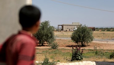 فتى ينظر في اتجاه مبنى نفذت فيه قوات التحالف عملية انزال جوي في الحميرة شمال محافظة حلب السورية (16 حزيران 2022، أ ف ب). 