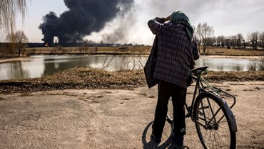 رجل ينظر الى دخان يتصاعد بعد هجمات روسية على منشأة لتخزين الوقود في مدينة كالينيفكا في أوكرانيا (25 آذار 2022، أ ف ب). 