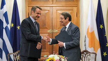 أناستاسيادس (الى اليمين) وميتسوتاكيس يتصافحان بعد توقيع اتفاقيات ثنائية في القصر الرئاسي في العاصمة نيقوسيا (17 حزيران 2022، أ ف ب).